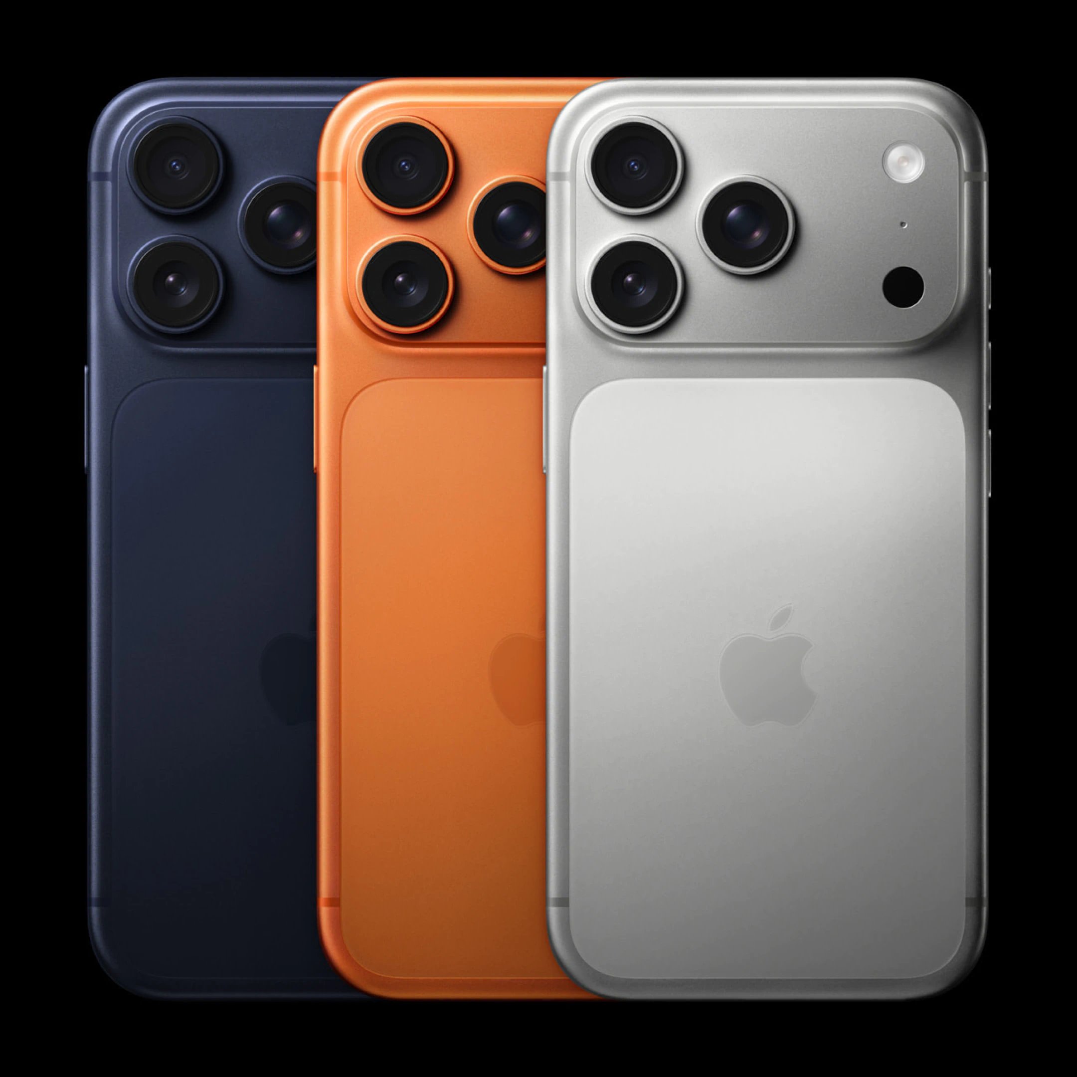 Tre iPhones set bagfra i mørk blå, orange og sølv med tydelige kameralinser og Apple-logoer på en sort baggrund.