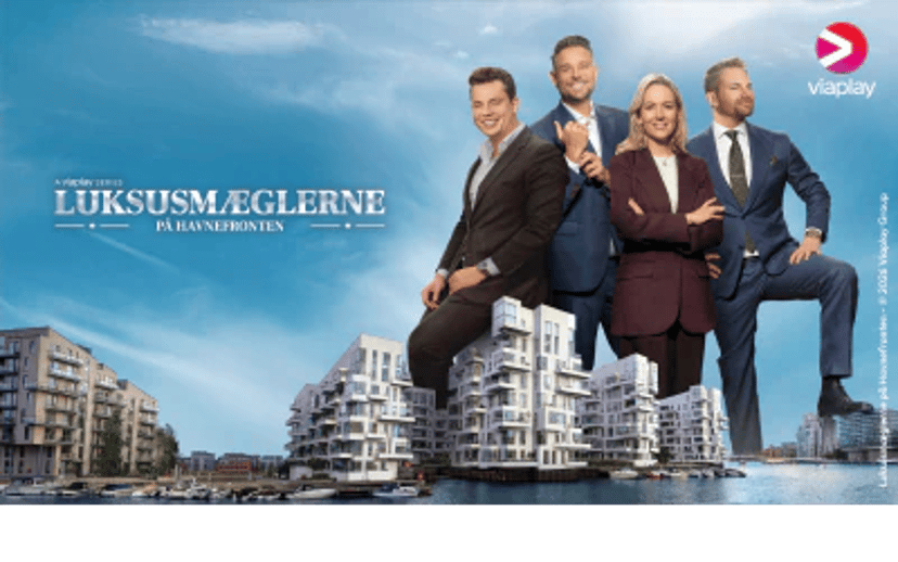 Fire personer i jakkesæt foran moderne boligbyggeri ved havnefronten med Viaplay-logo og serienavnet Luksusmæglerne.