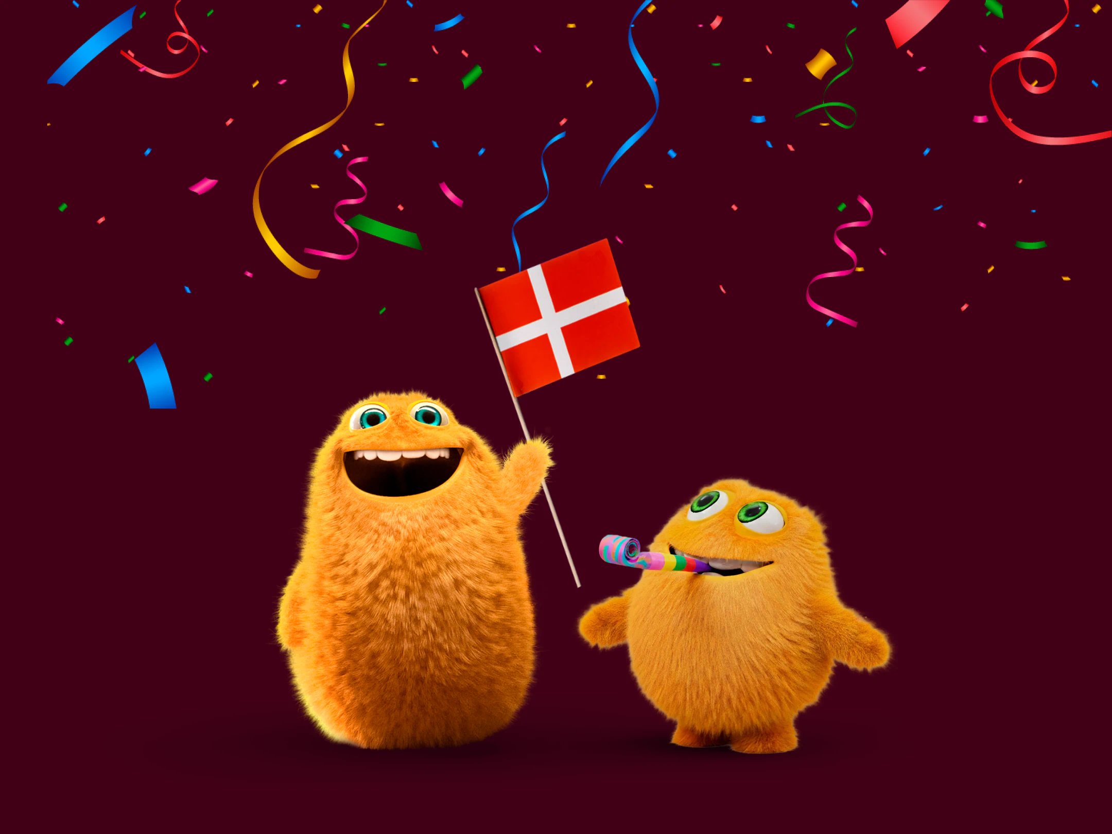 To orange Små Priser fejrer med konfetti, fløjte og et dansk flag på en mørkerød baggrund.