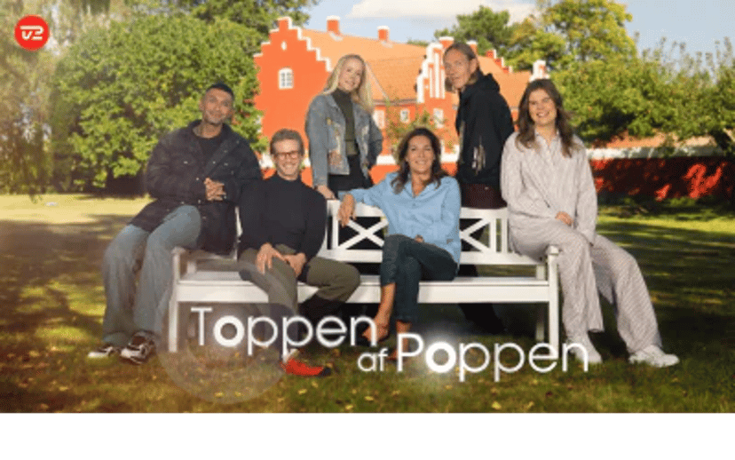 Fem personer poserer på en hvid bænk foran en rød bygning og grønne træer med teksten Toppen af Poppen på billedet.