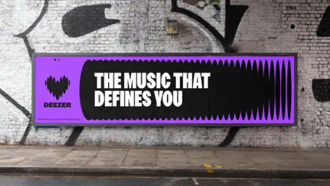 Reklameskilt med teksten 'The music that defines you' i stærke farver på en murstensvæg, der formidler personlig musikoplevelse gennem Deezer og CBB MIX.