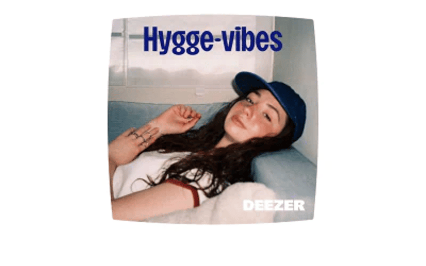 Kvinde ligger afslappet på en sofa med teksten "Hygge-vibes" og Deezer-logoet i nederste højre hjørne.