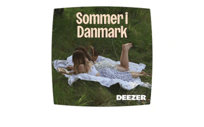 To personer ligger på et tæppe i højt græs med teksten “Sommer i Danmark” og Deezer-logoet.