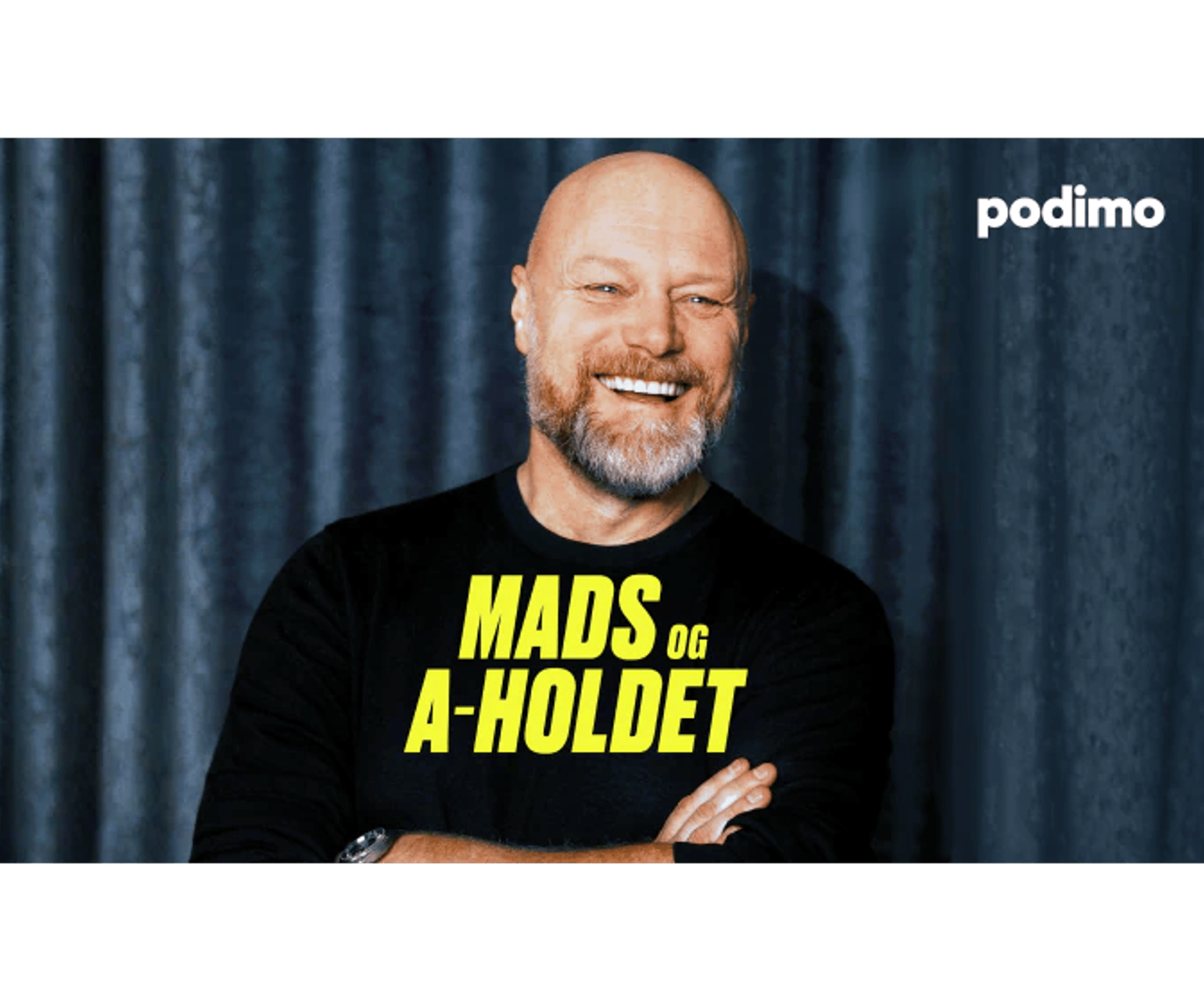 Smilende, skaldet mand med skæg og sort trøje med teksten “Mads og A-holdet” foran mørk gardinbaggrund og Podimo-logo.